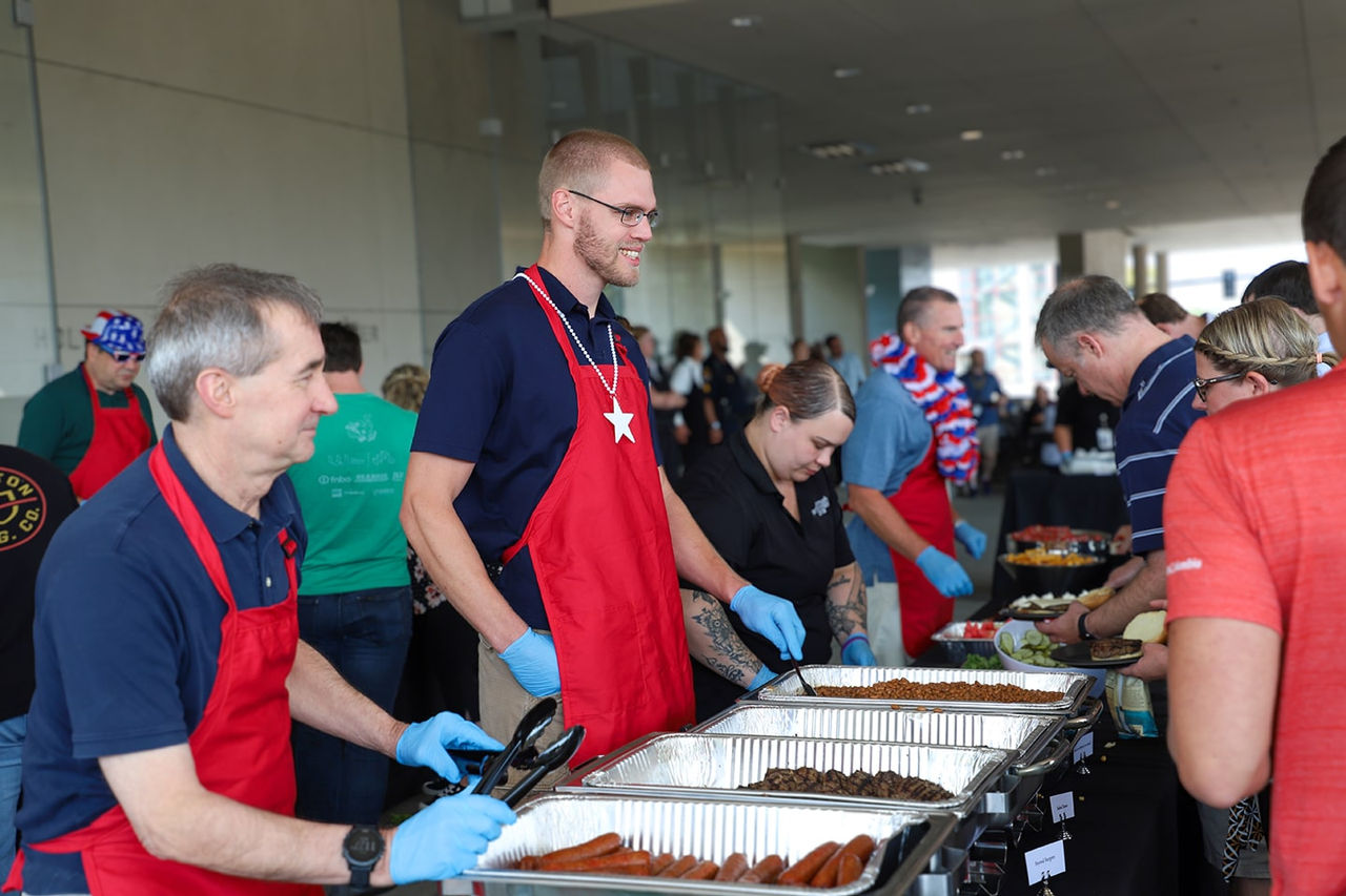 People in red aprons serving food to employees