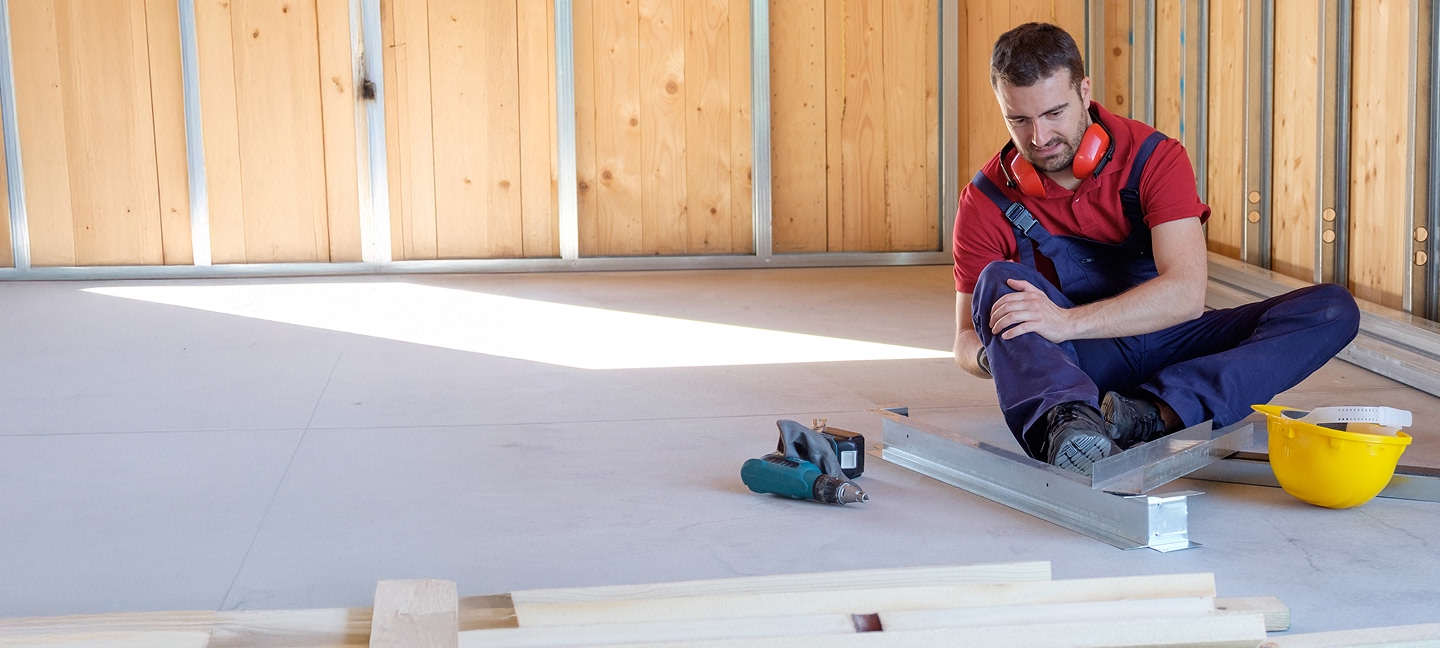 Contractor on the ground of a house being built holding his knee