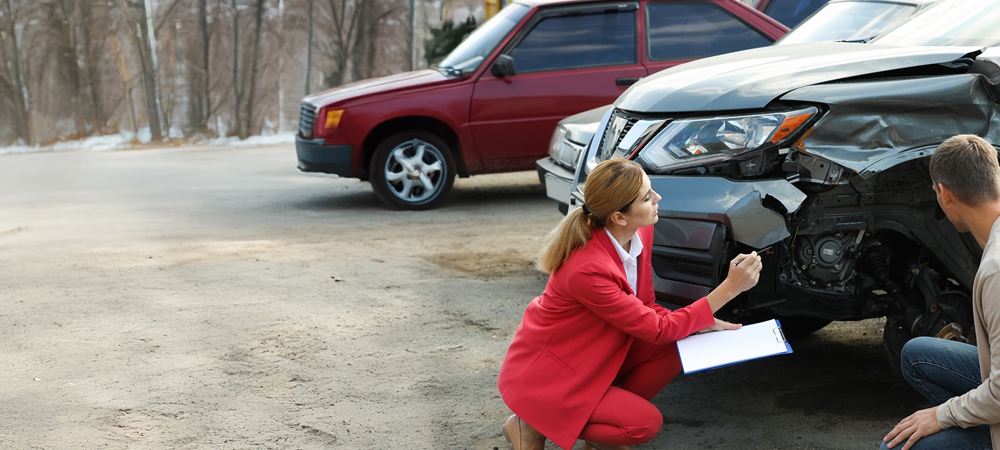 Man and woman in a red suit looking at a car after an accident