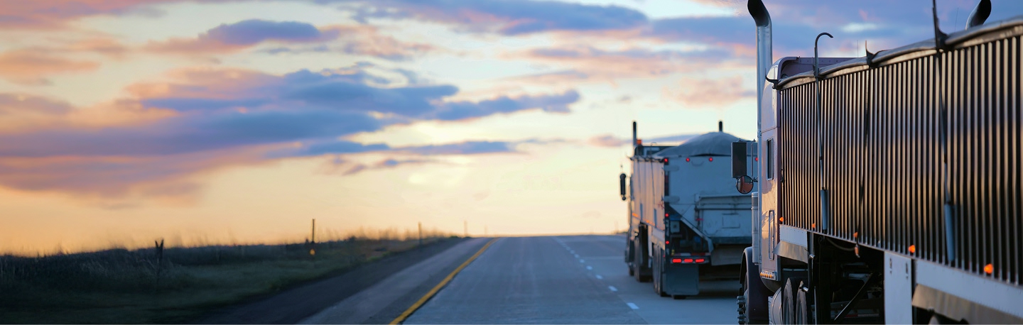 Two trucks driving at sunset