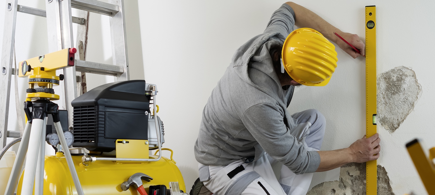 Contractor working on a wall with a level and other tools